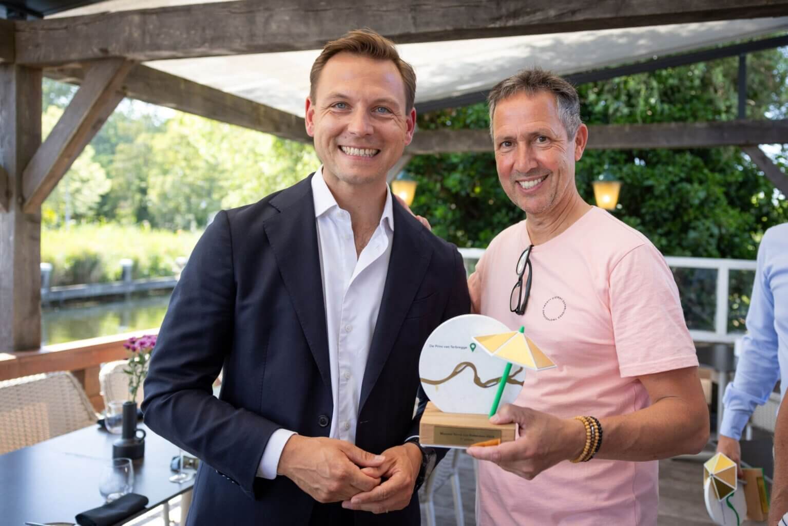 Wethouder Tim Versnel van de Gemeente Rotterdam overhandigt de trofee van de prijs voor het Mooiste Terras van Rotterdam uit aan eigenaar Simon Wijers